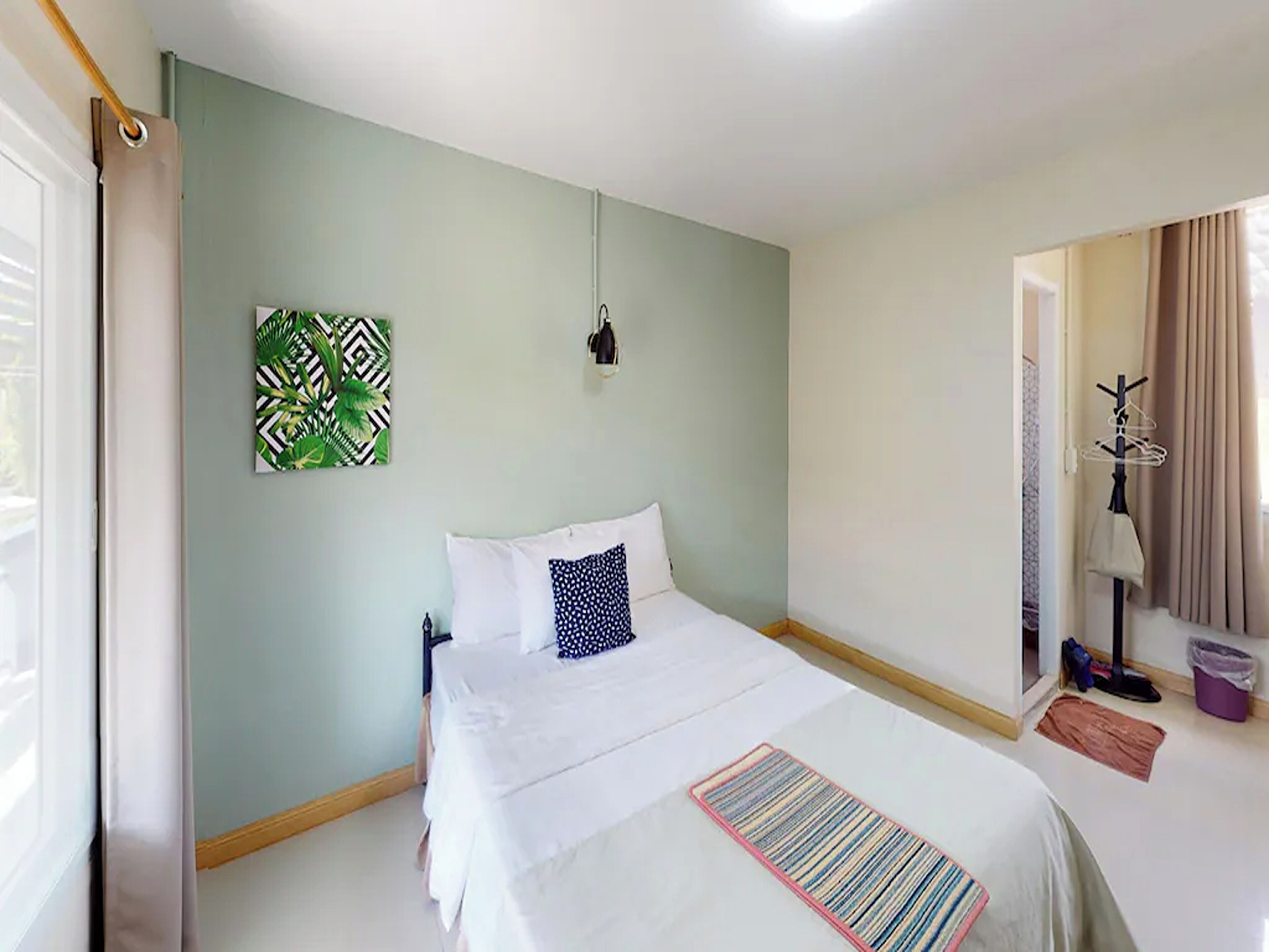 Ein Schlafzimmer mit einem Bett, einer Wandleuchte und einem Kleiderhaken.