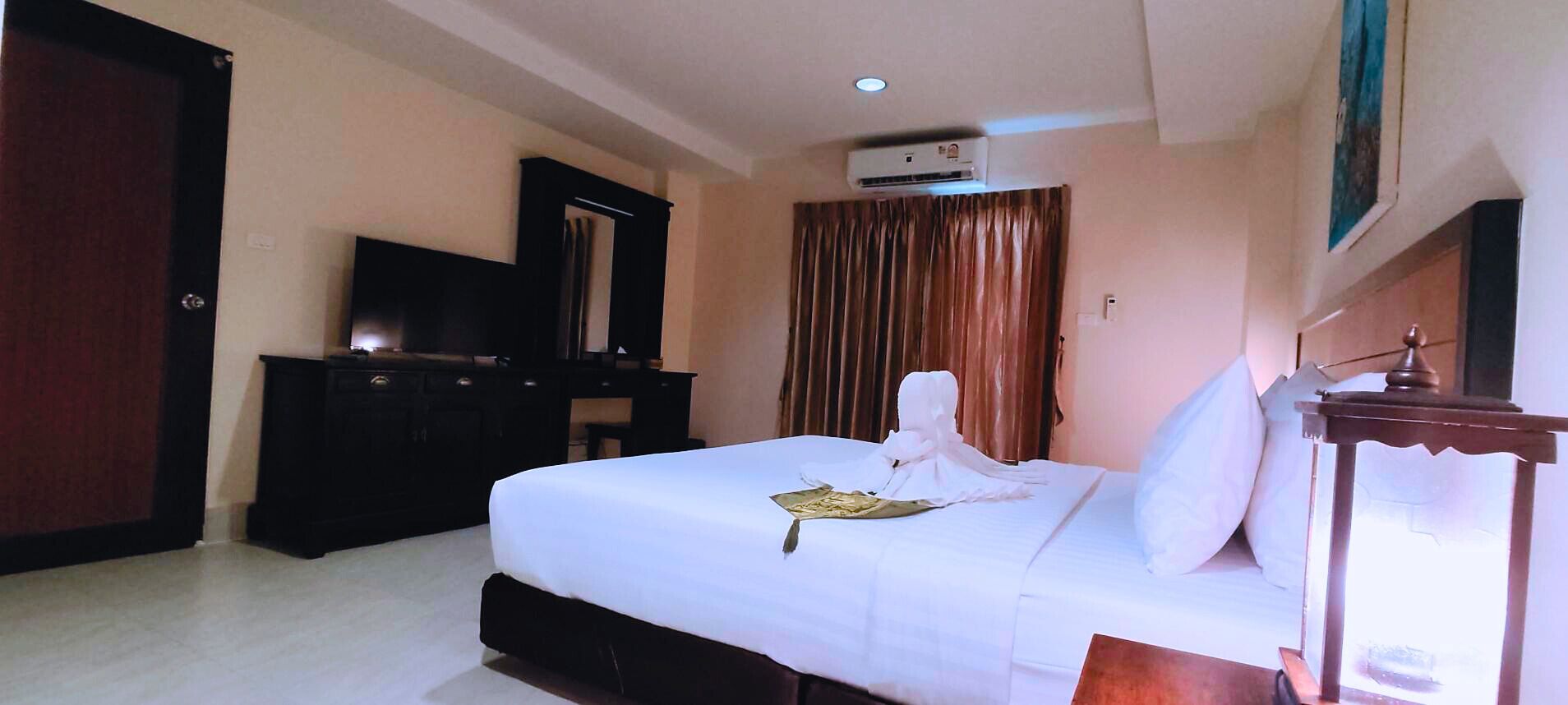Une chambre d’hôtel équipée d’un lit, d’une commode, d’un appareil de climatisation et d’une fenêtre avec des rideaux.