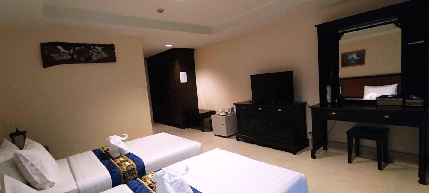 Una habitación de hotel con dos camas, televisión, cómoda y espejo.