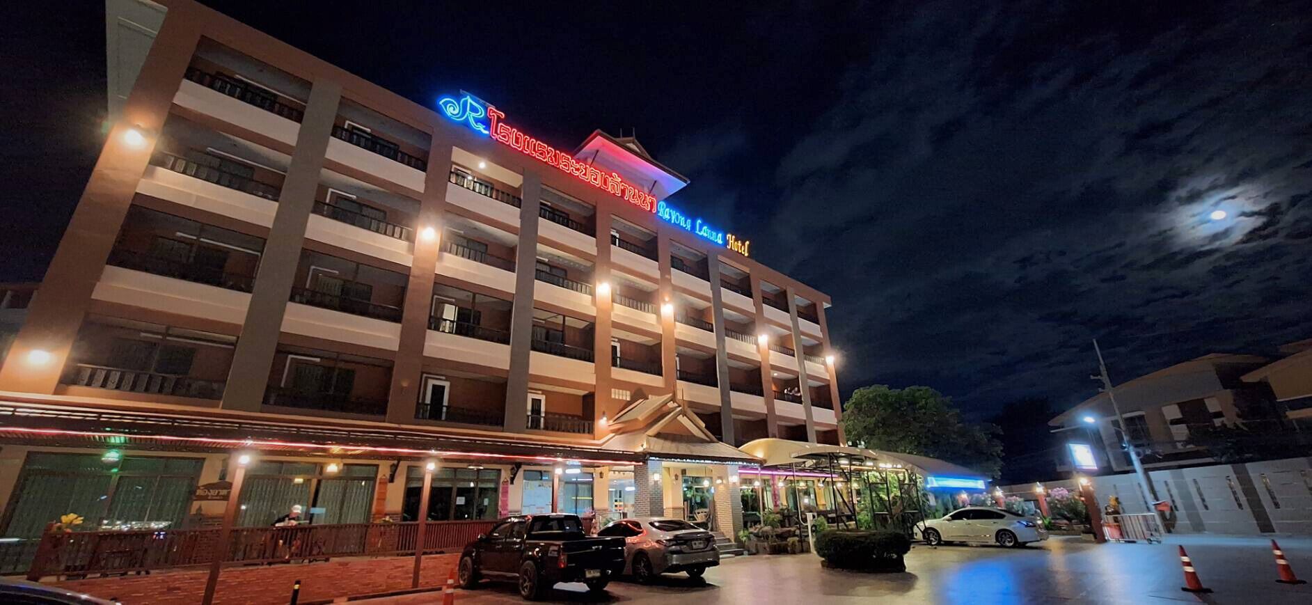 A multi-story hotel with a prominent neon sign, multiple balconies, and a well-lit entrance area.