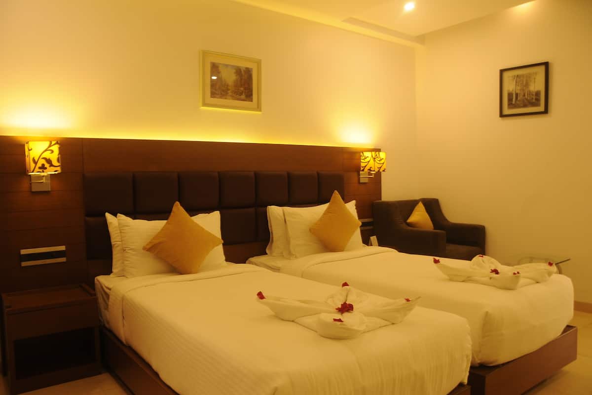 Habitación de hotel con dos camas, un sofá y un cabecero.