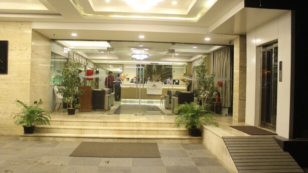 Un vestíbulo de hotel con una recepción, zona de estar y plantas en macetas.