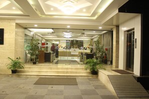 A hotel lobby with a reception desk, seating area, and potted plants. - NK Grand Park Hotel (Chennai)