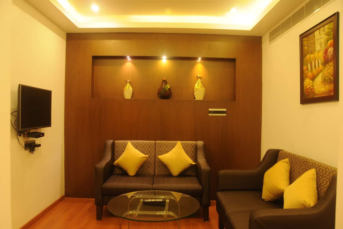 Una sala de estar con un sofá, una mesa de centro de vidrio y objetos decorativos en una estantería.