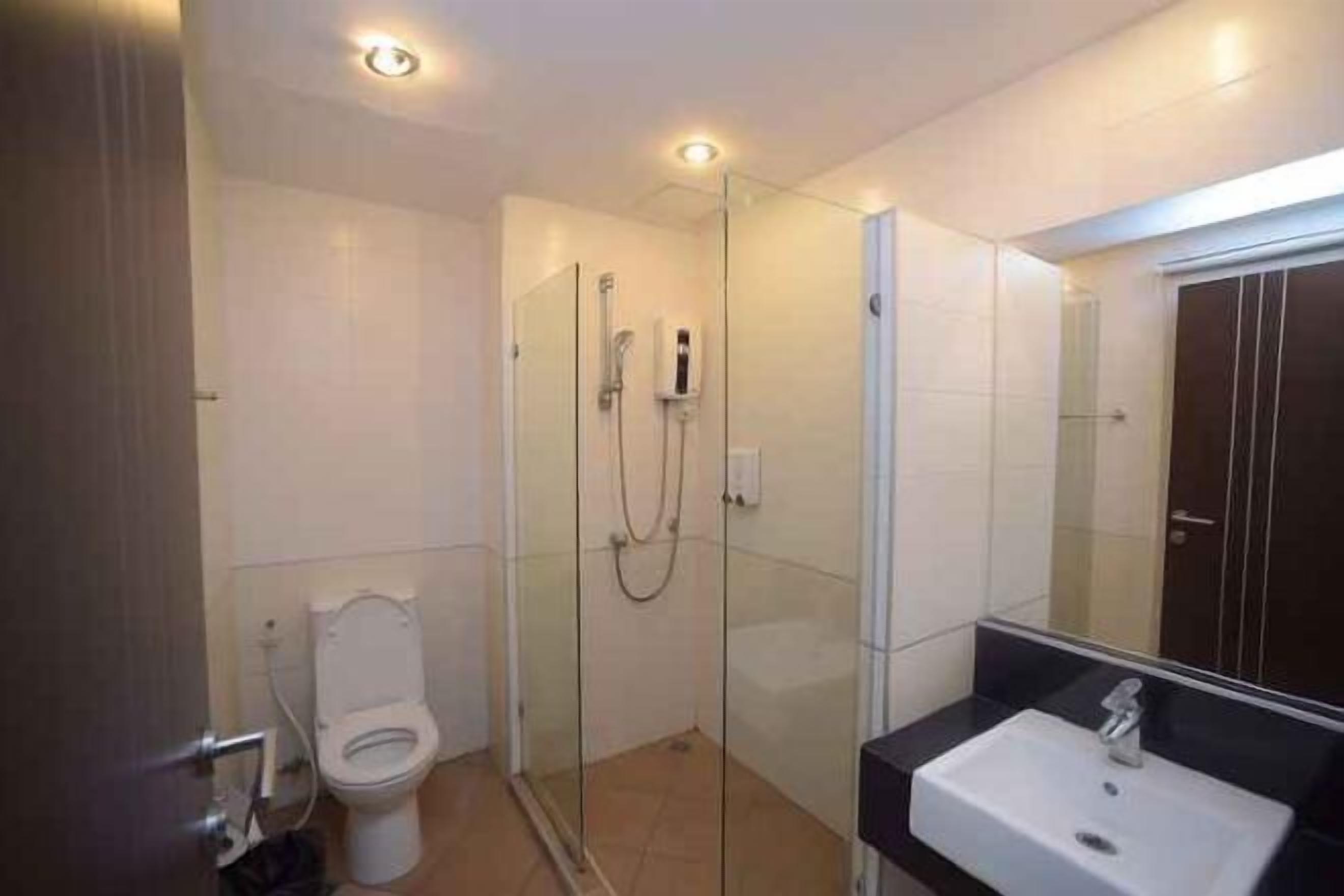 Ein modernes Badezimmer mit einer Glaskabine zur Dusche, einer weißen Toilette und einem Waschbecken mit Spiegel.
