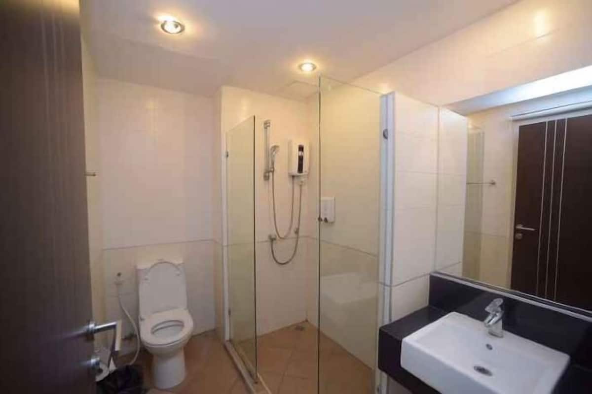Ein modernes Badezimmer mit einer Glaskabine zur Dusche, einer weißen Toilette und einem Waschbecken mit Spiegel.