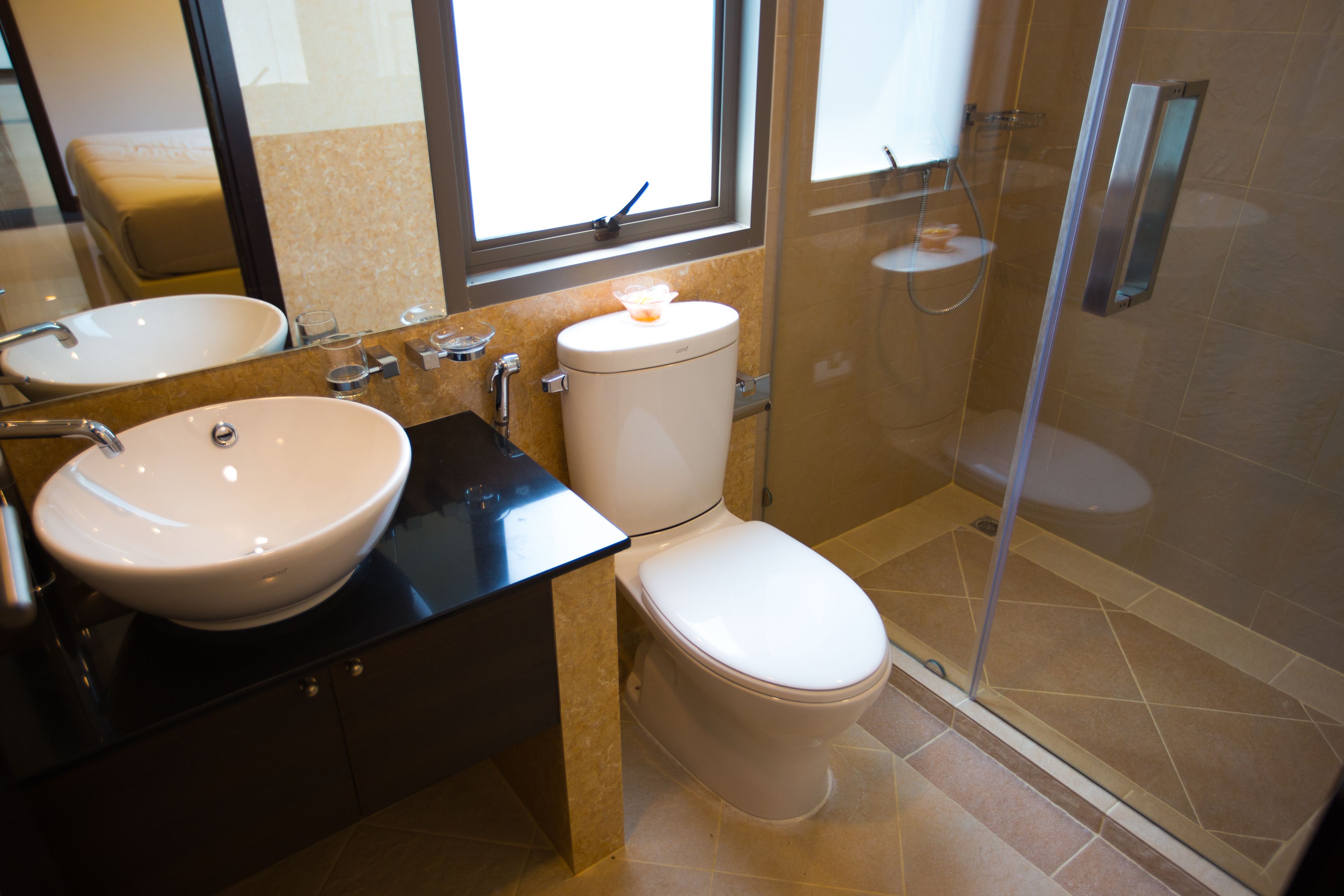 A modern bathroom with a large sink, toilet, and glass-enclosed shower.