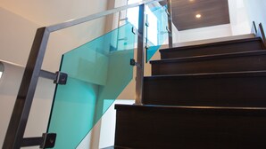 A staircase with glass railings and wooden steps, leading to a room with a ceiling light fixture. - Villa Navin Resort (Pattaya)