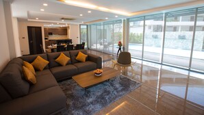 A modern living room with a sectional sofa, a coffee table, and a view of the outdoor area. - Villa Navin Resort (Pattaya)