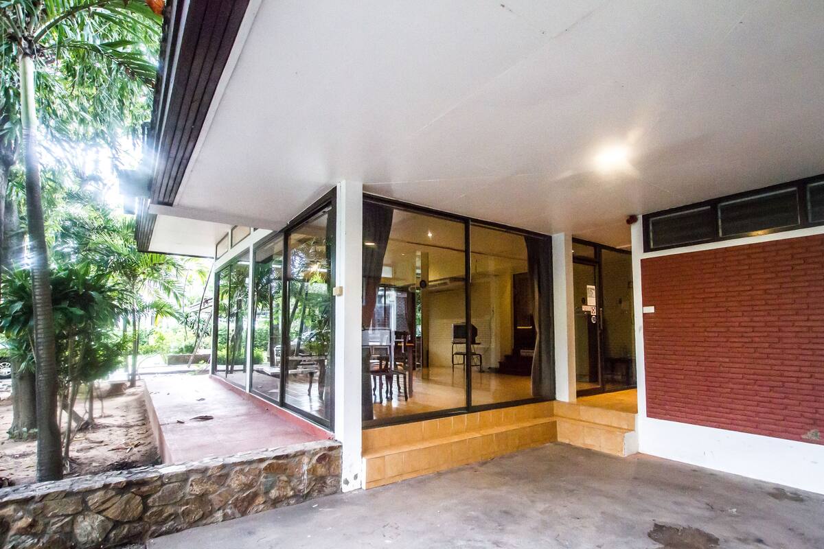 A covered outdoor area with a stone wall, glass doors leading to an interior space, and a red brick wall.