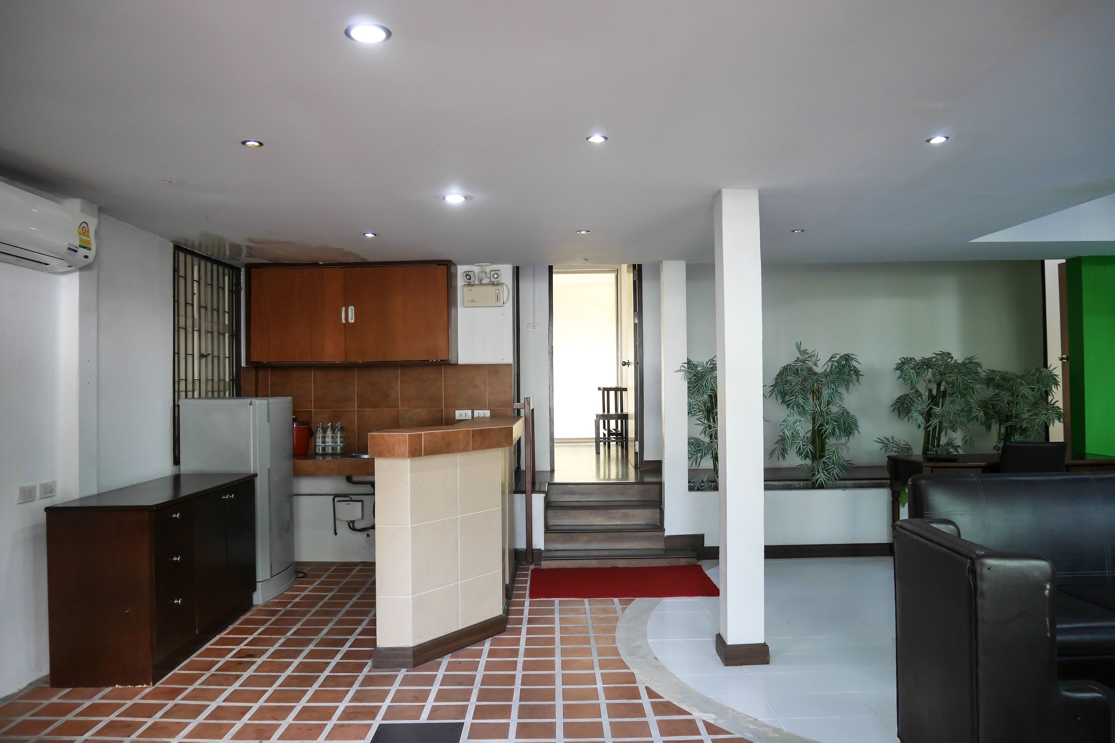 A modern kitchen with a refrigerator, stove, and cabinets. There is a staircase leading to a dining area with a red carpet.