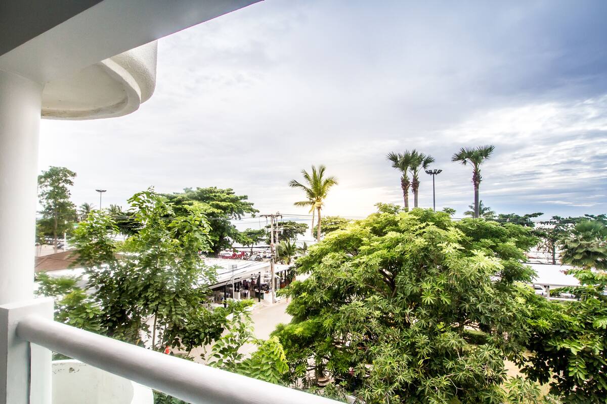 A balcony with a view of a street, palm trees, and buildings.