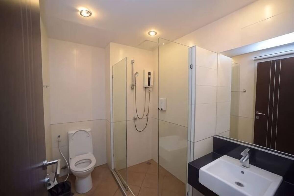 A modern bathroom with a glass shower enclosure, a white toilet, and a sink with a mirror above it.