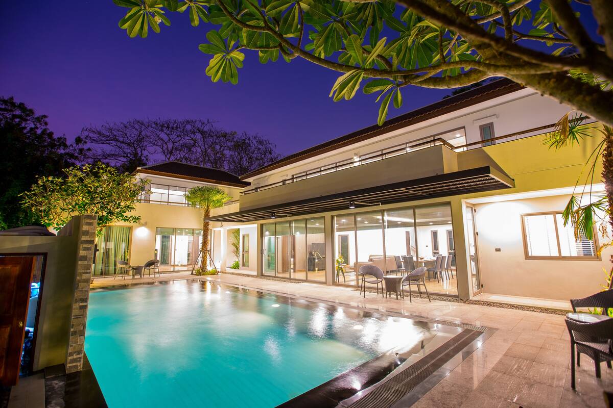 A modern pool area with a clear pool, surrounded by glass doors and outdoor seating.