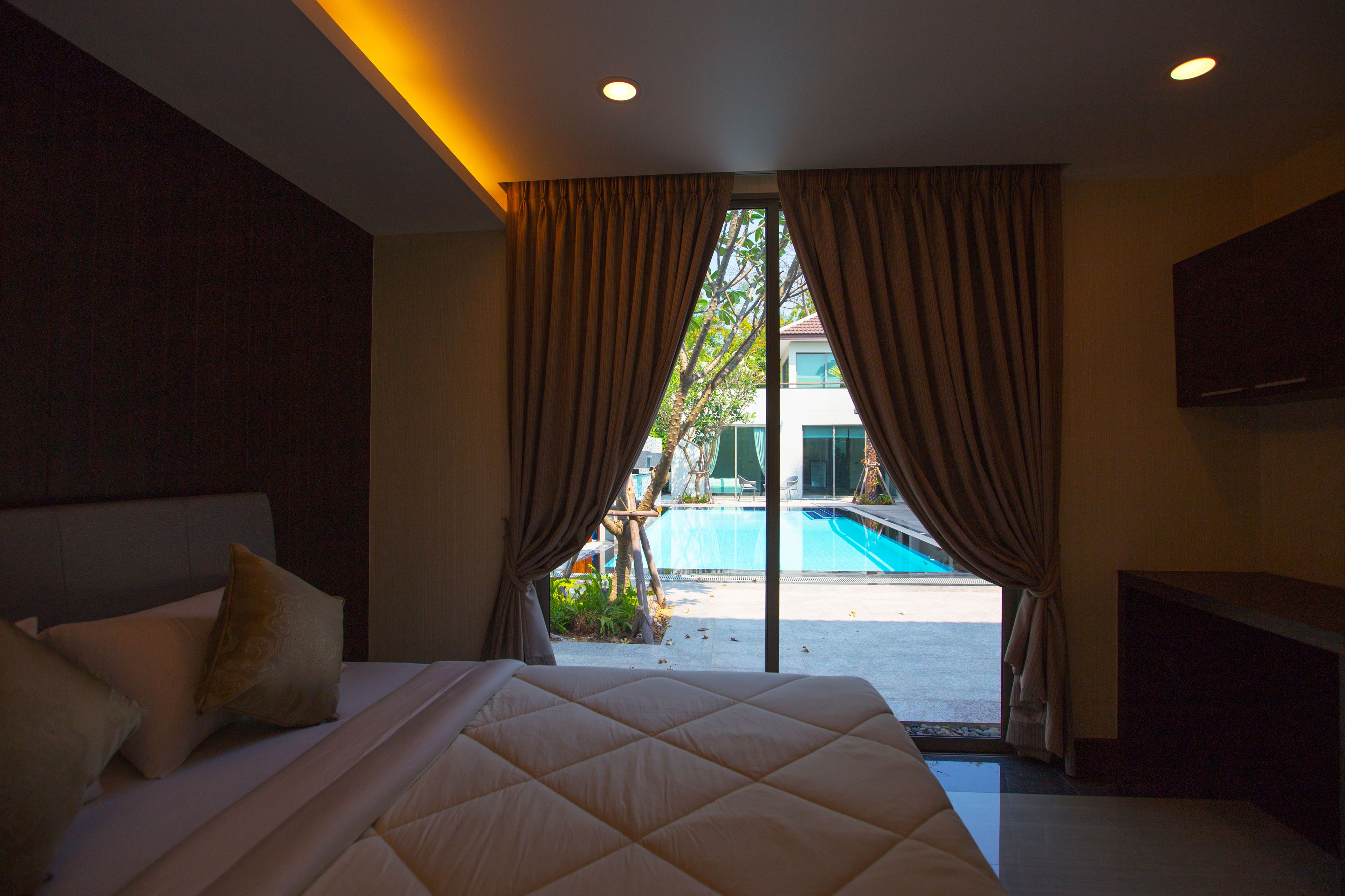 A hotel room with a large bed, a view of a swimming pool, and a sliding door leading outside.