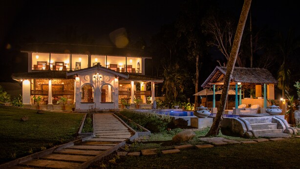 Una casa grande y bien iluminada de dos pisos, con un porche cubierto y una piscina.