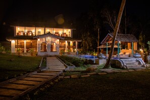 A large, well-lit two-story house with a covered porch and a swimming pool. - Villa Kubura (Gonapinuwala)