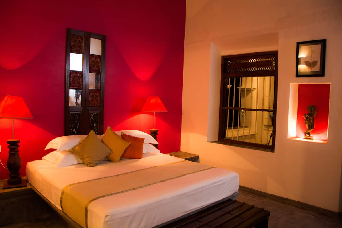 A hotel room with a large bed, two bedside lamps, a window with a view, and a decorative mirror.