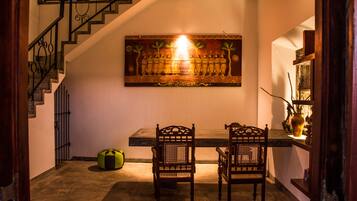 A dining area with a wooden table and two chairs, a staircase with a railing, and a wall-mounted painting.