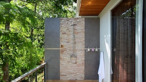 A modern shower area with a brick wall and a glass door, surrounded by a balcony with a wooden railing. - Presidential Penhouse - Kamala (Kamala)