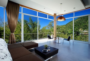 Una sala de estar moderna con un ventanal grande, un sofá, una mesa de centro y dos sillones.