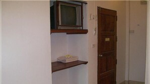 Un corridoio stretto con una porta in legno e una piccola mensola con una scatola sopra.