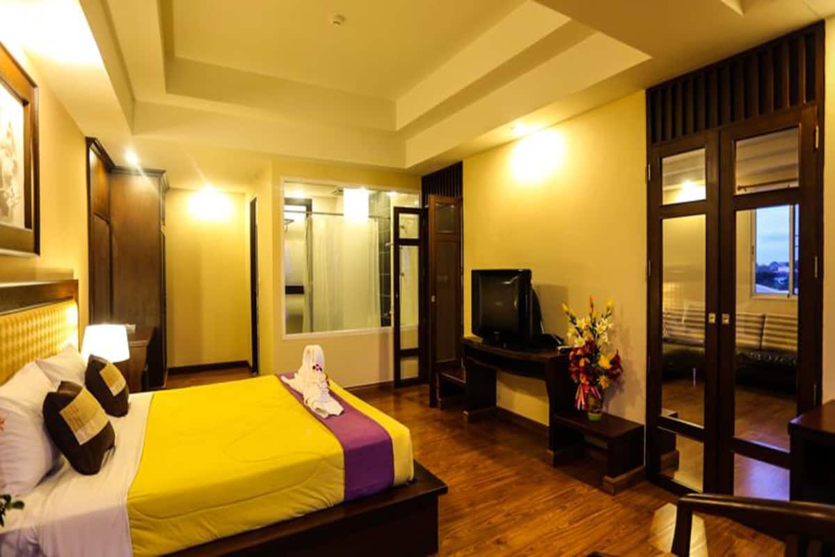 A hotel room with a bed, a TV, a desk, and a mirror.