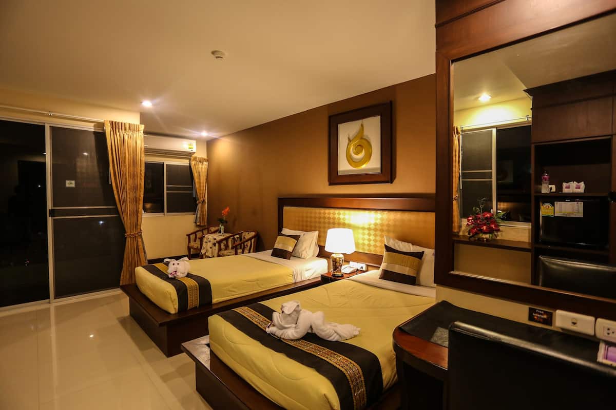 A hotel room with two beds, a large mirror, a desk, and a view of the outside.