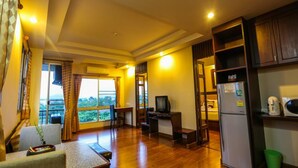 A spacious living area with a large window, a television, and a refrigerator. - Madina Hotel (Rayong)