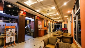 A hotel lobby with a reception desk, seating area, and a television screen. - Madina Hotel (Rayong)