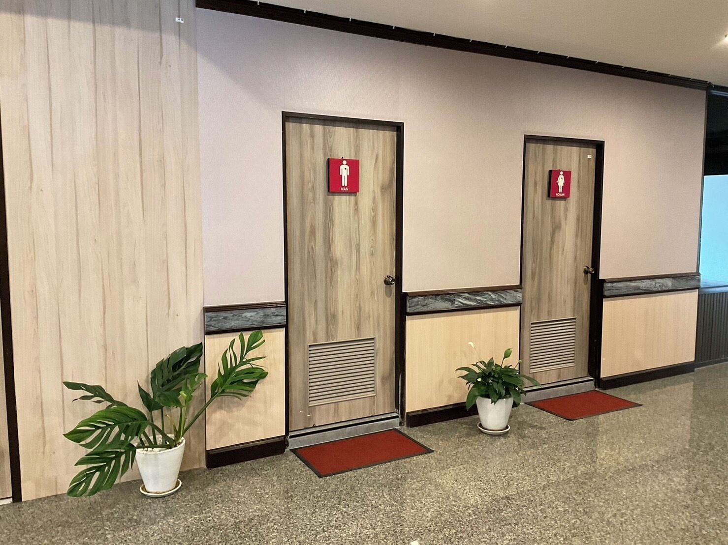 A row of wooden doors with red signage indicating men's and women's restrooms.