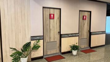 Una hilera de puertas de madera con señalización roja que indica baños de hombres y mujeres.