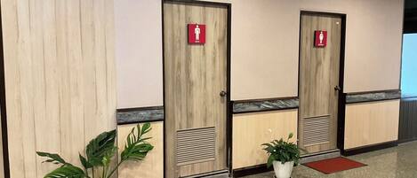 A row of wooden doors with red signage indicating men's and women's restrooms.