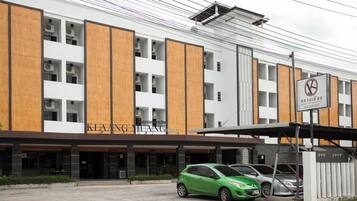 Un hotel moderno con fachada blanca y detalles de madera, que destaca por su entrada principal y un coche verde estacionado al frente.