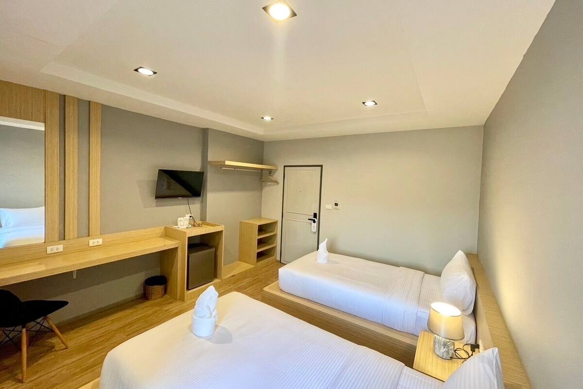Een hotelkamer met twee bedden, een bureau, een televisie en een douche.