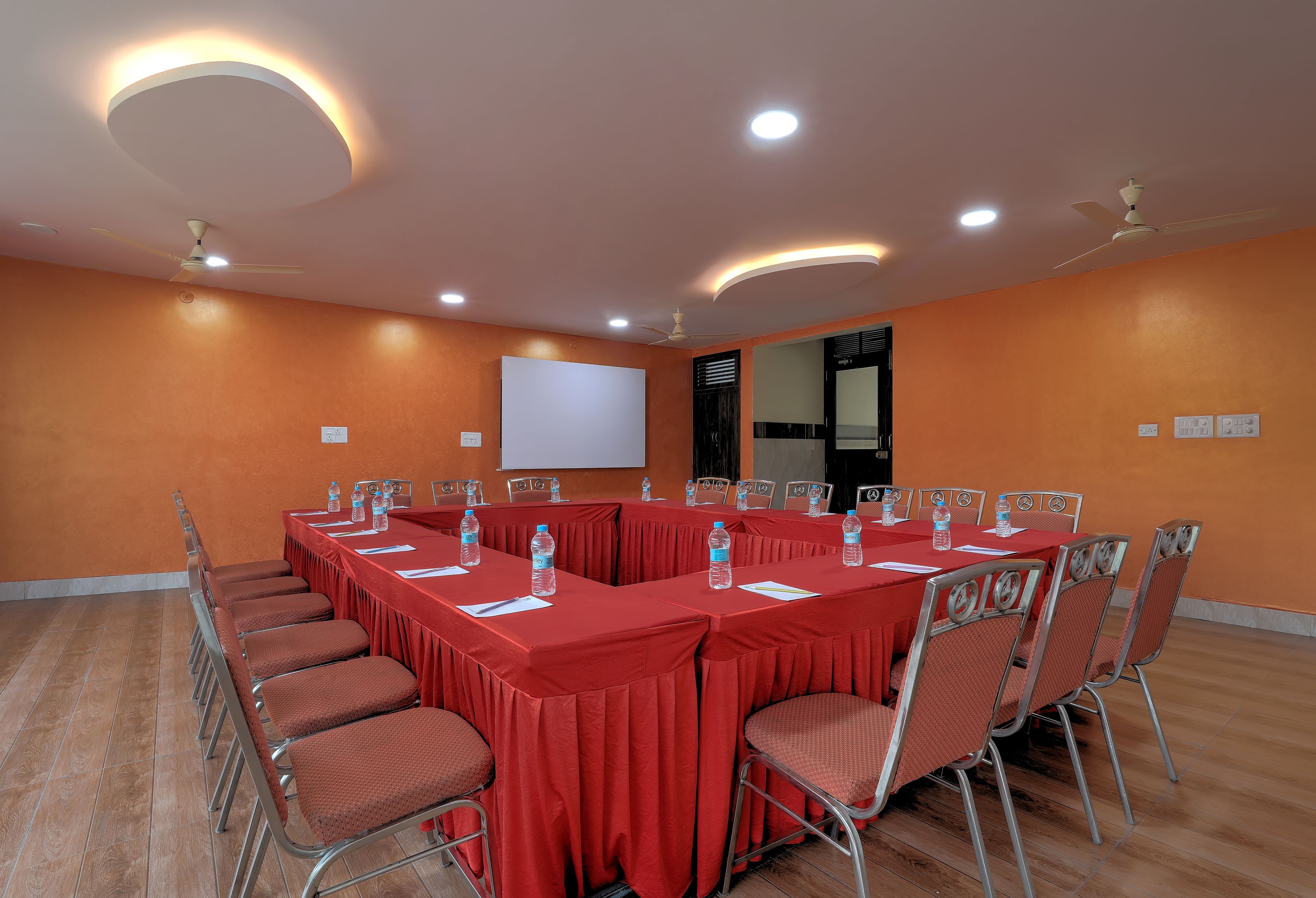 A conference room with a long table, chairs, and a projector screen.