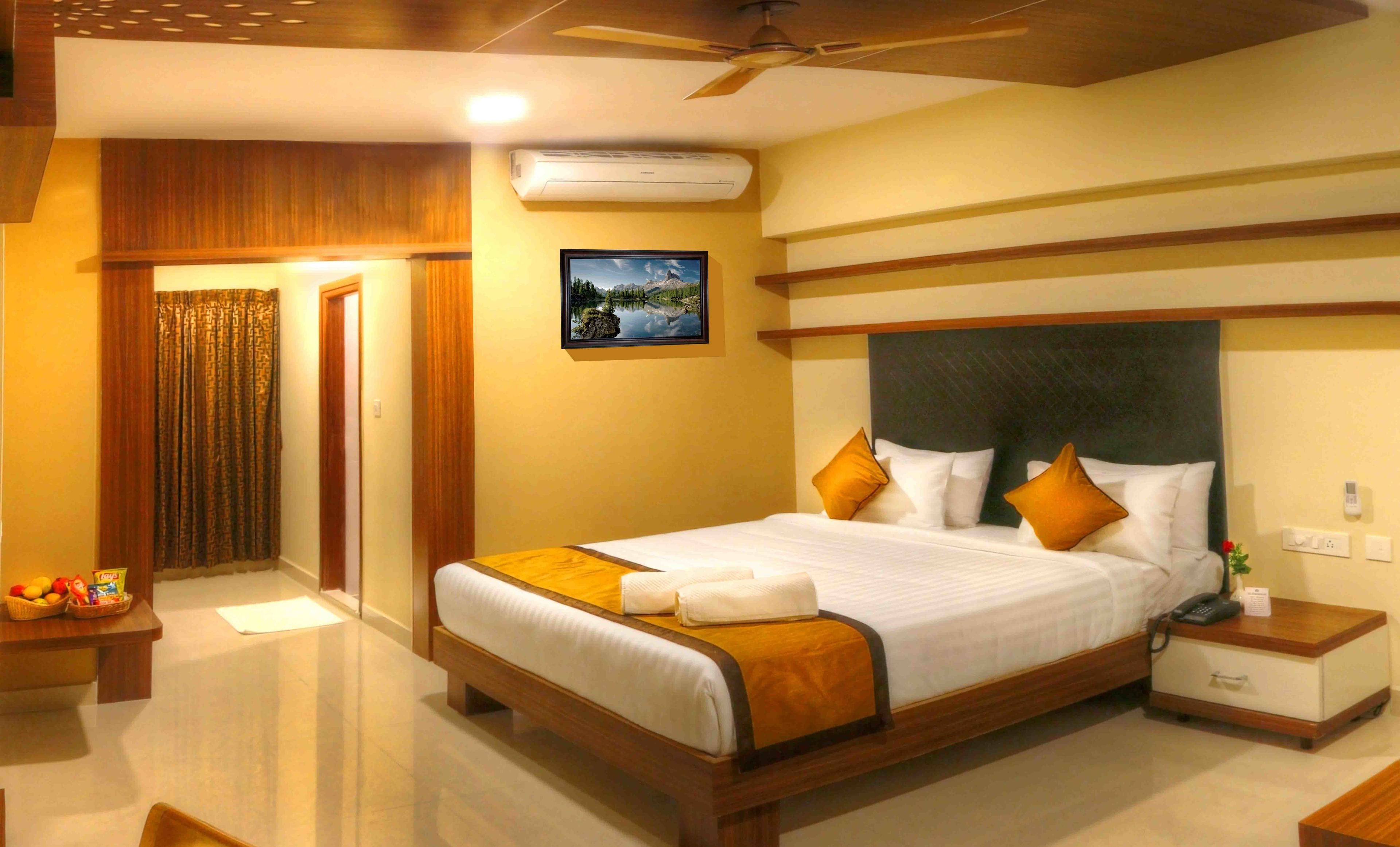 A hotel room with a large bed, wooden headboard, and a nightstand with a phone and a lamp.