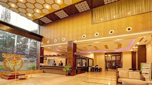 Un vestíbulo de hotel con mostrador de recepción, zona de estar y un altar decorativo.