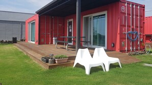 Un bâtiment rouge doté d’un patio couvert, d’une porte et d’une fenêtre.