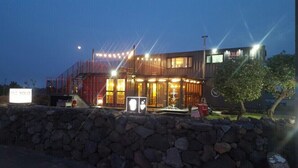 Un bâtiment moderne avec un mur en pierre à l’avant, une enseigne et une entrée bien éclairée.
