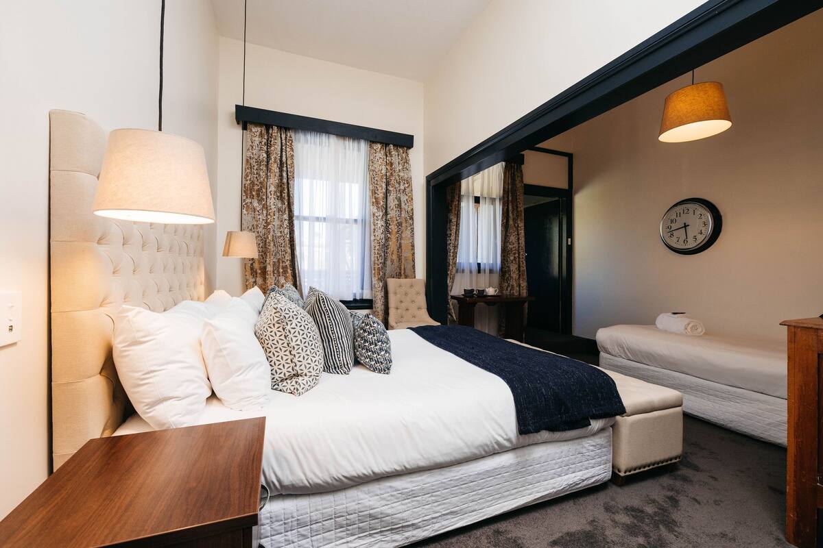 Une chambre à coucher moderne avec un grand lit, des tables de chevet, un miroir et une horloge murale.