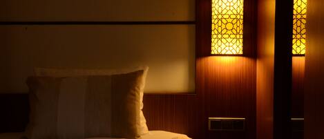Una habitación de hotel con una cama, una mesita de noche y dos lámparas de pared.