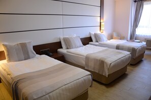 Een hotelkamer met drie bedden, een nachtkastje, een stoel en een lamp.