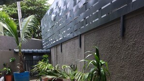 A wooden deck leading to a garden area with various potted plants and a textured wall. - Seaview Holiday Apartments (Grand-Baie)