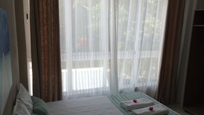 A hotel room with a bed, a sofa, and a window with sheer curtains. - Seaview Holiday Apartments (Grand-Baie)
