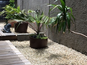 A garden area with potted plants, a small Buddha statue, and a wooden deck.