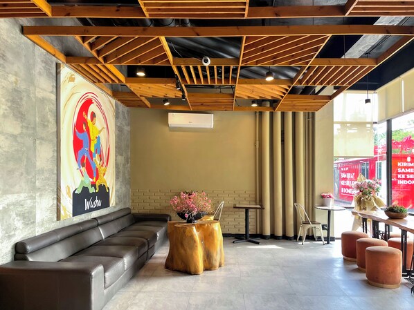 Un interior moderno con techo de madera, un mural, un sofá, una mesa redonda de madera y una pared de ladrillo.