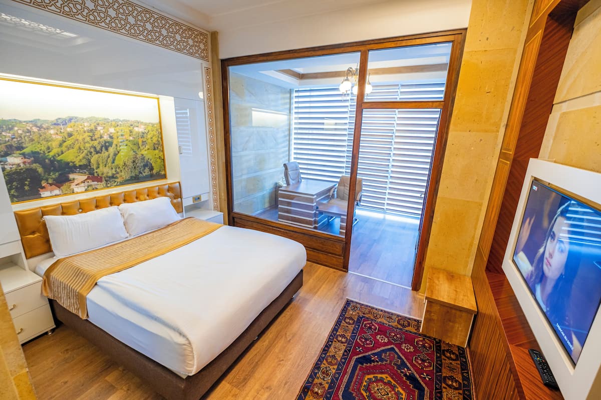 Habitación de hotel con una cama grande, vistas a un balcón con una silla y un televisor.