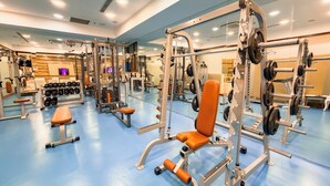 Un gimnasio con diverso equipo de ejercicio, bancos y estantes para pesas.