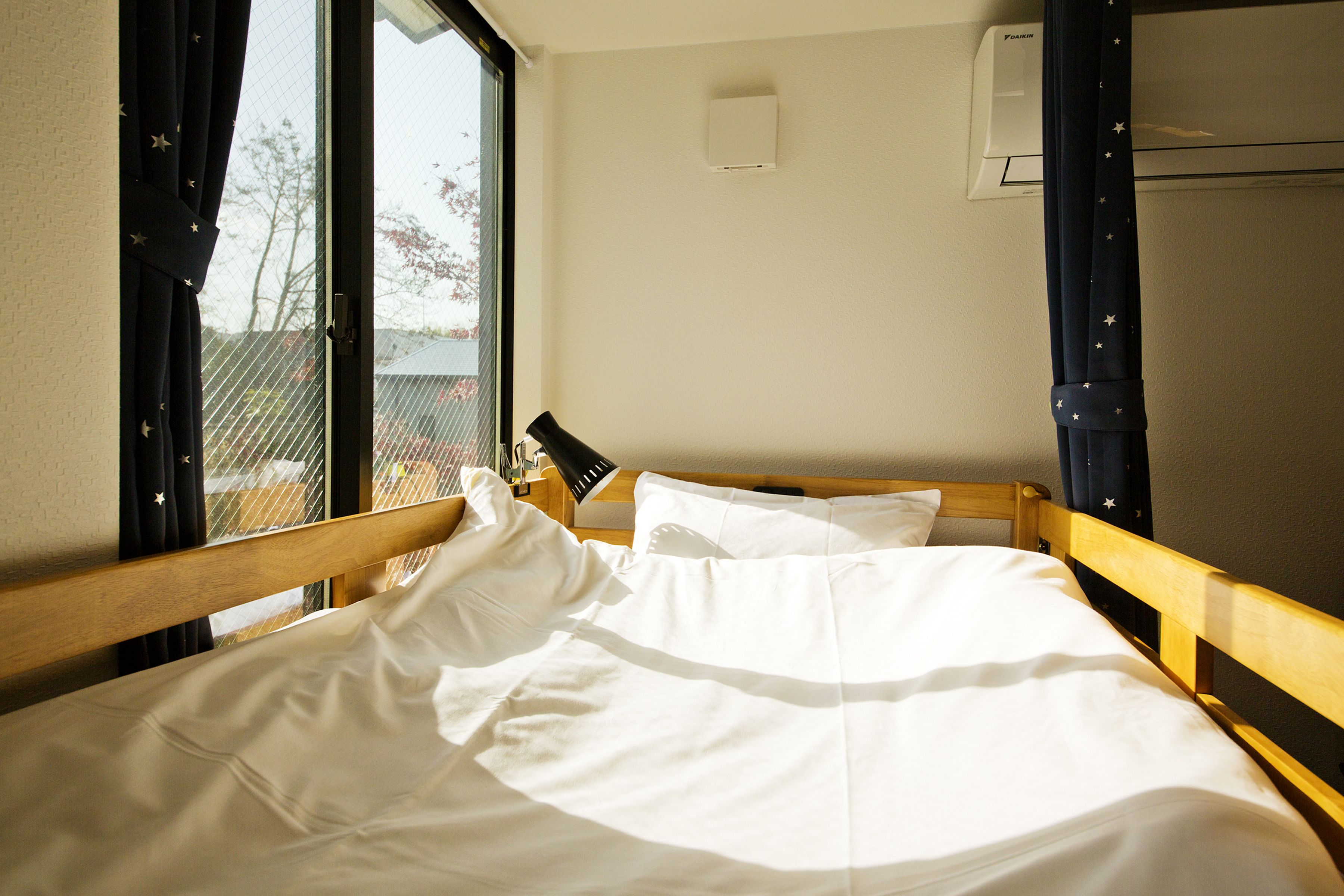 Una habitación de hotel con una cama, una ventana y un equipo de aire acondicionado.